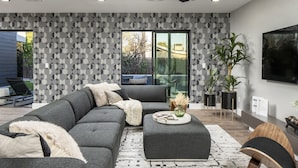 Ein modernes Wohnzimmer mit Ecksofa, Couchtisch und Deckenventilator.