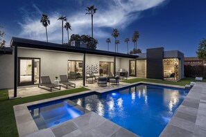 Una casa moderna con piscina, muebles de exterior y palmeras.