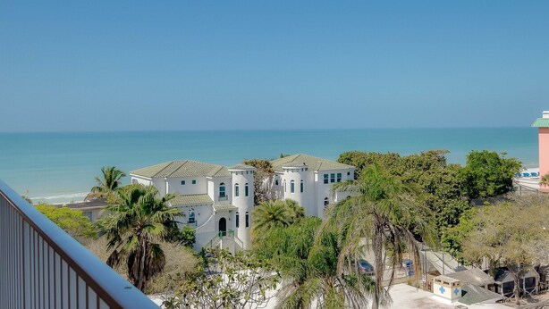 Una proprietà costiera con diversi edifici bianchi, palme e vista sull'oceano.