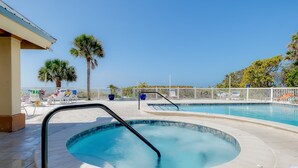 Una piscina con idromassaggio, lettini e palme.