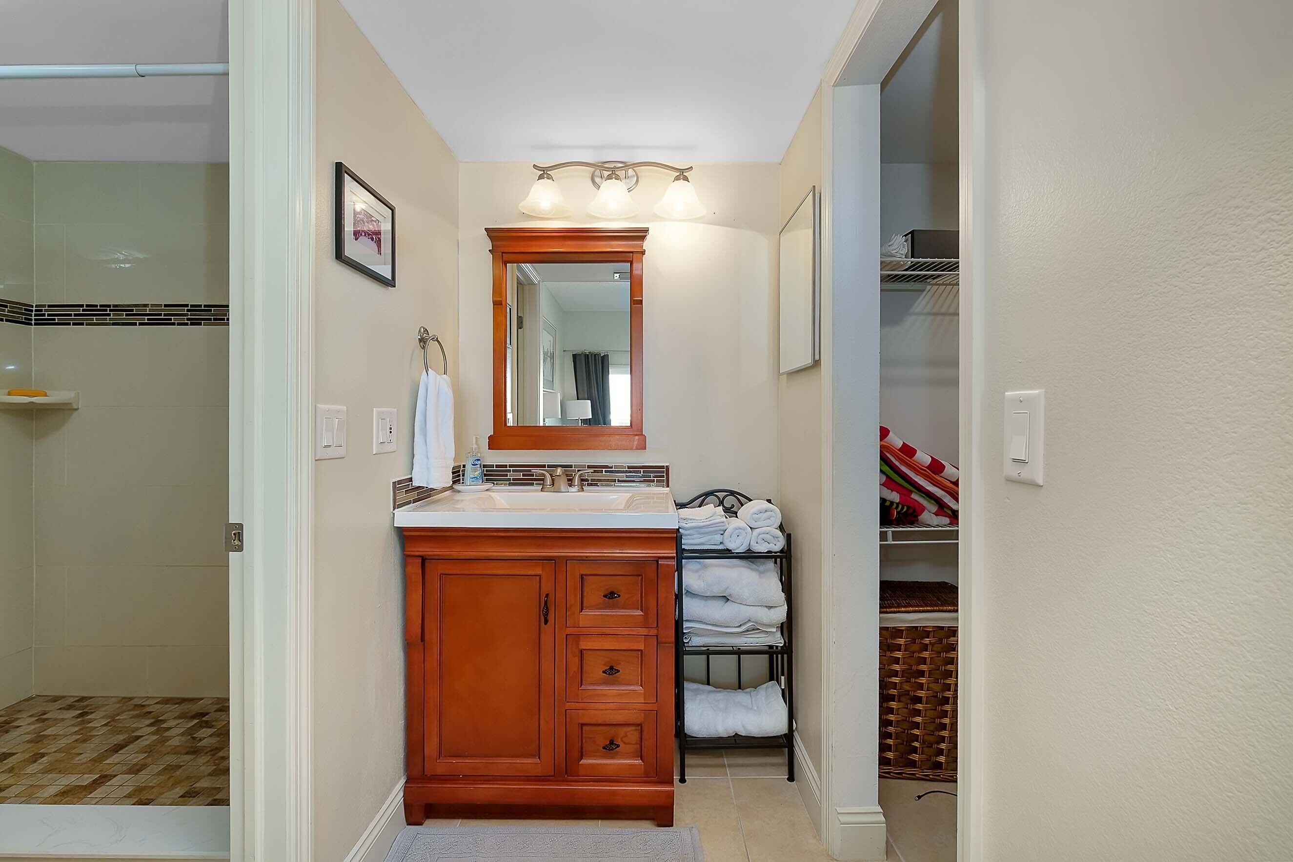 A bathroom with a wooden vanity, a glass shower enclosure, and a towel rack with neatly folded towels.