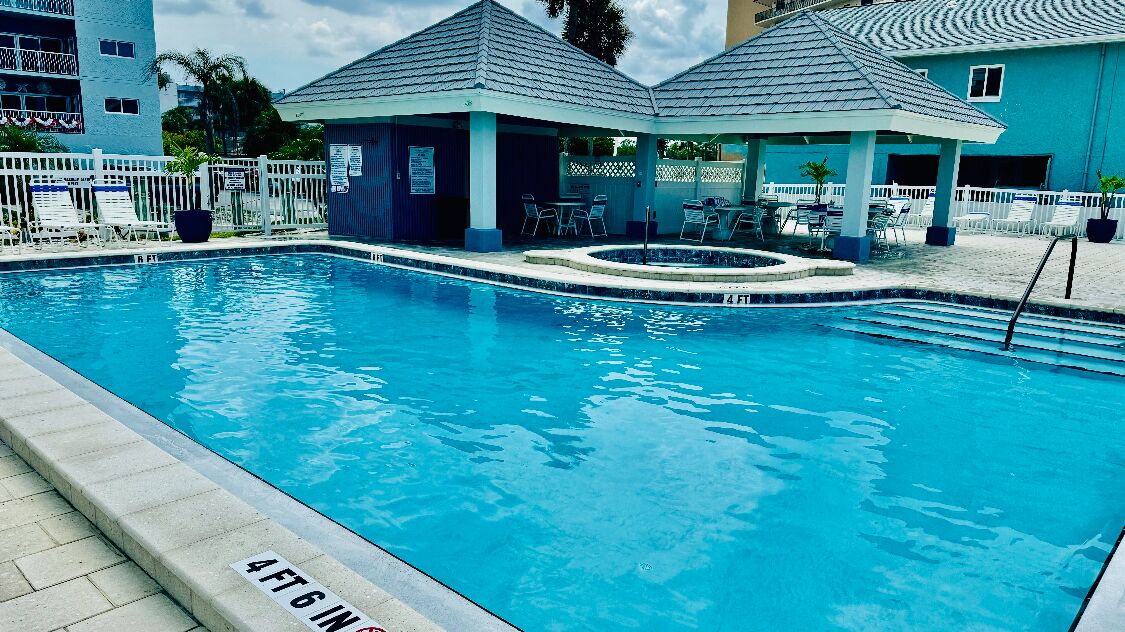 Ein Swimmingpool mit einer Tiefenmarkierung von 1,4 Metern, umgeben von Liegestühlen und Sonnenschirmen.