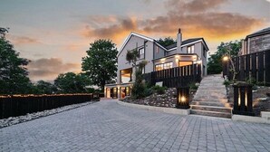 Une maison moderne à deux étages, dotée d’une allée pavée et d’une clôture en bois.