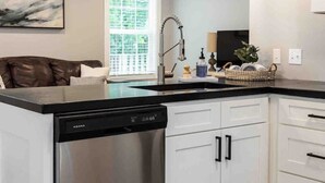 A modern kitchen with white cabinets, a dishwasher, a black countertop, and pendant lighting. - Bearden Exec · Bearden Executive Rental >8min to UT & Downtown (Knoxville)