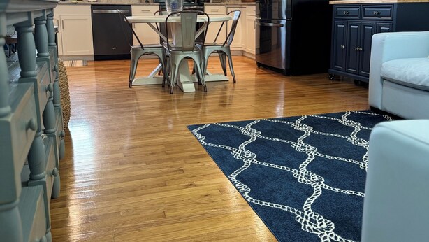 A modern kitchen with white cabinets, a black refrigerator, and a dining area with a table and chairs. - Boro Bungalow in beautiful downtown Swansboro with street legal golf cart (Swansboro)