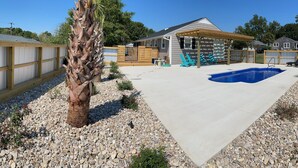 A backyard with a swimming pool, wooden deck, and a fenced area. - Boro Bungalow in beautiful downtown Swansboro with street legal golf cart (Swansboro)