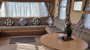 Una sala acogedora con un conjunto de sofás, una mesa de centro y un ventanal con cortinas.
