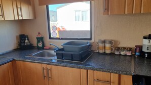 Una cocina con armarios de madera, una ventana, un lavabo, un tostador y varios utensilios de cocina.