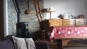 Ein gemütliches Zimmer mit Kamin, Holzmöbeln und einer gemusterten Tischdecke.