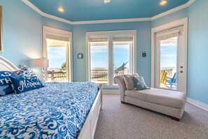 Relax in this serene bedroom with a large bed, a window offering a view, and a cozy bench.