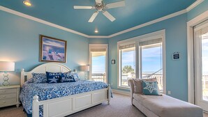 A bedroom with a bed, a bench, and a view of the ocean. - Beautiful Beachfront -- Biscayne Fantasea (Bolivar Peninsula)