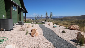 Ein Haus mit einem Schotterweg, großen Steinen und freiem Blick auf die umliegende Landschaft.