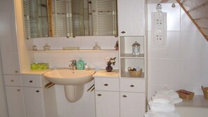 Casa de banho com lavatório, espelho, armários e porta-toalhas.