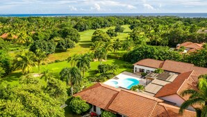 A large house with a swimming pool, surrounded by lush greenery and a golf course. - Luxurious Casa de Campo Villa for up to 12 people (La Romana)