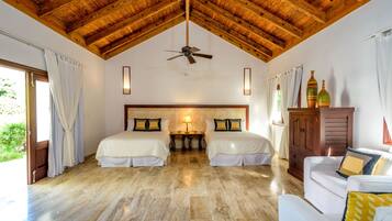 A room with two beds, a ceiling fan, a wooden cabinet, and a couch.