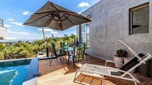 En træterrasse med swimmingpool, havemøbler og udsigt over landskabet.