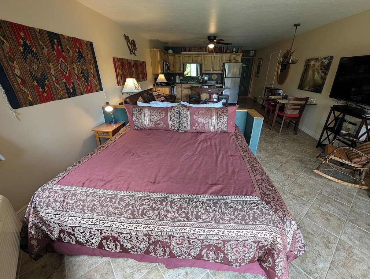 A bedroom with a large bed, a desk, and a chair in the corner.
