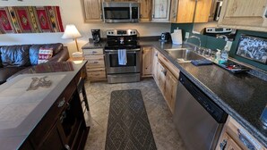 Une cuisine compacte avec des meubles en bois, un four à micro-ondes, une cuisinière et un lave-vaisselle.