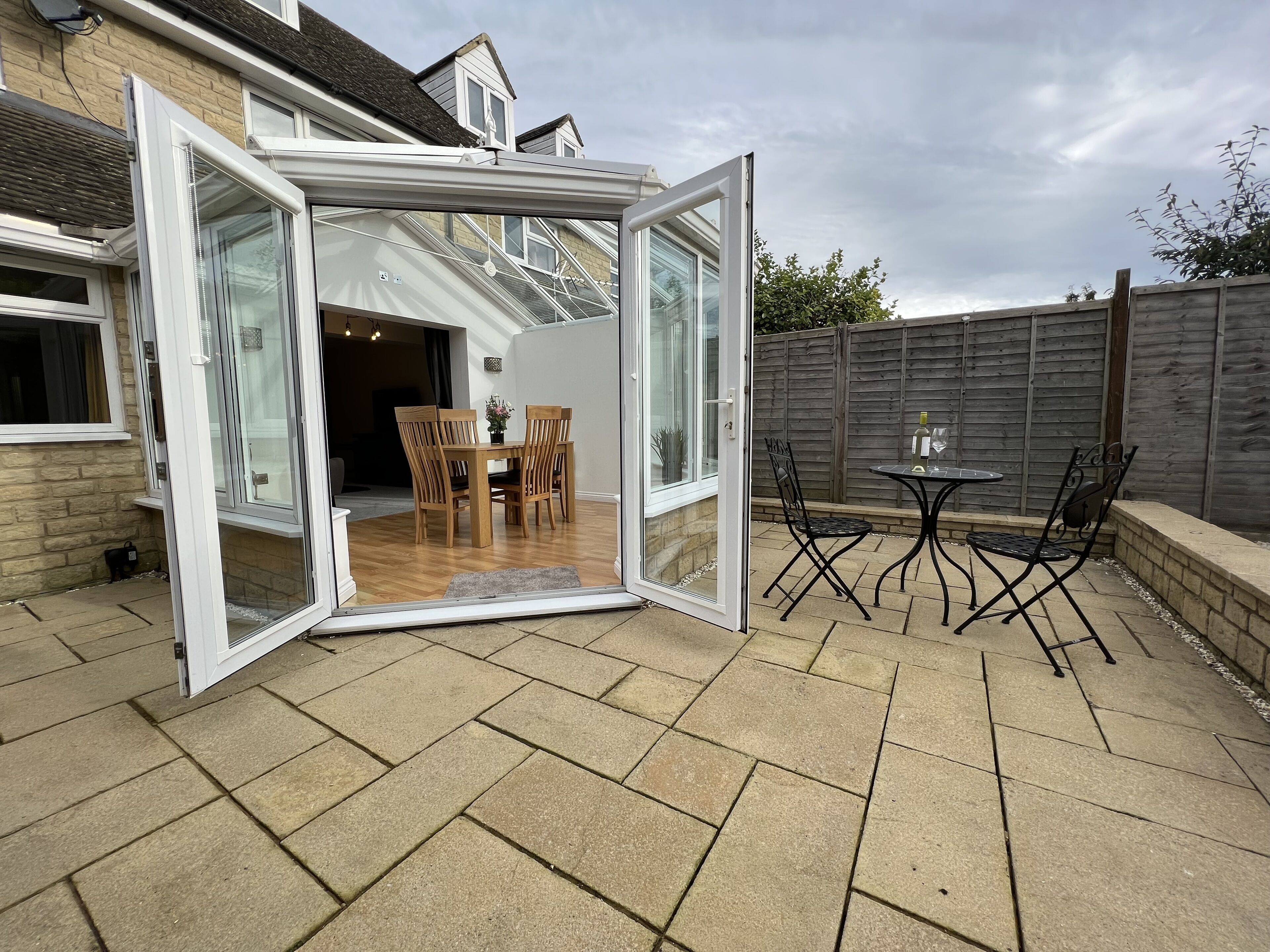 A patio with a glass door leading to a dining area with wooden chairs and a table.