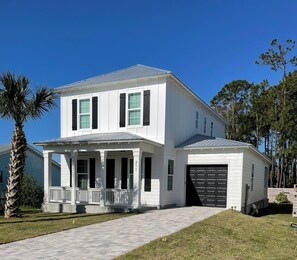A two-story white house with a covered porch and a garage.