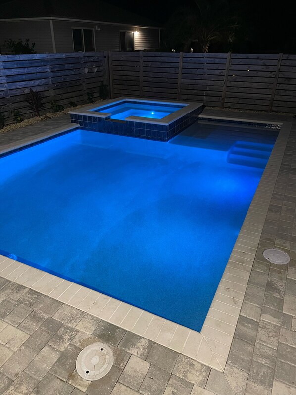 Une piscine rectangulaire dotée d’un jacuzzi intégré et d’une petite cascade décorative.