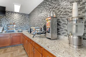 A kitchen with a brick backsplash, a coffee machine, a waffle maker, and a toaster.