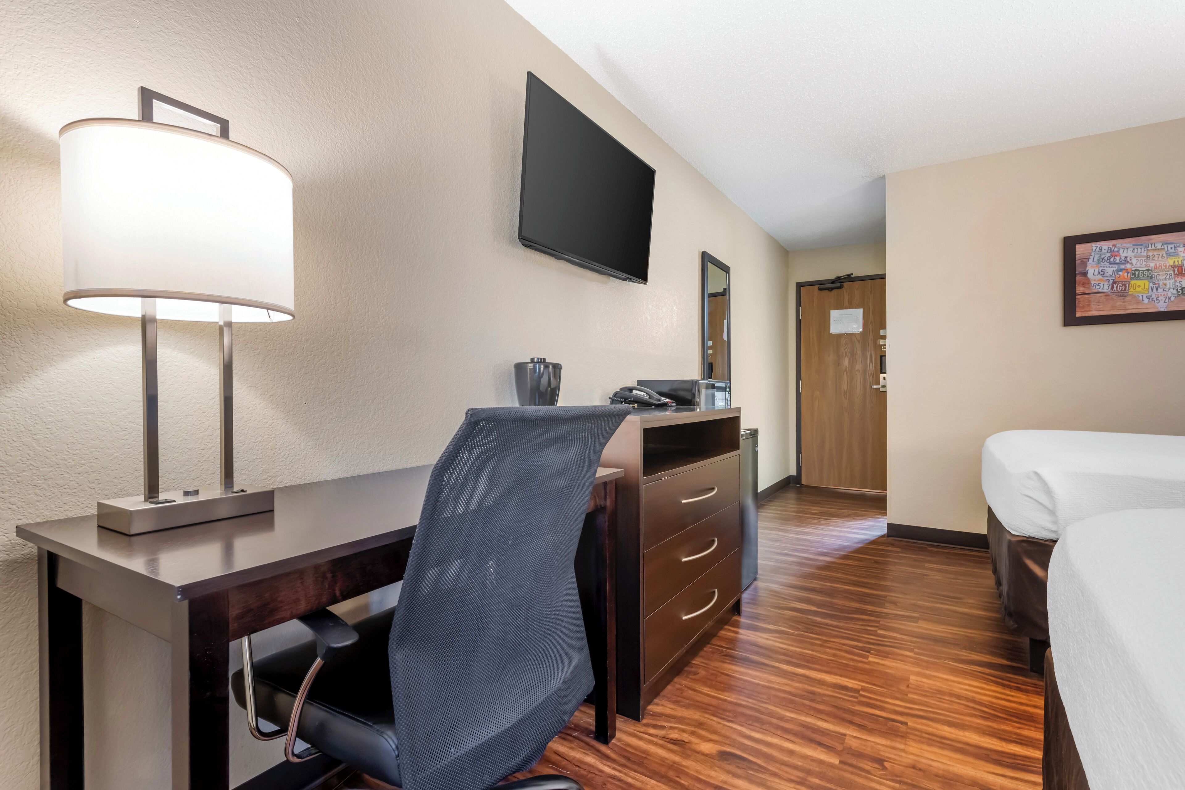 A hotel room with a desk, chair, and a bed.