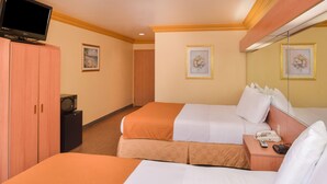 Ein Hotelzimmer mit zwei Betten, einem Fernseher, einem Schreibtisch mit Telefon und gerahmten Bildern an den Wänden.