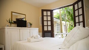 Quarto de hotel com uma cama grande, uma televisão em uma cômoda e vista para o verde lá fora.
