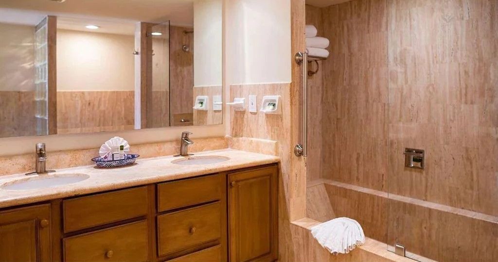 A bathroom with two sinks, a large mirror, wooden cabinets, and a shower area.