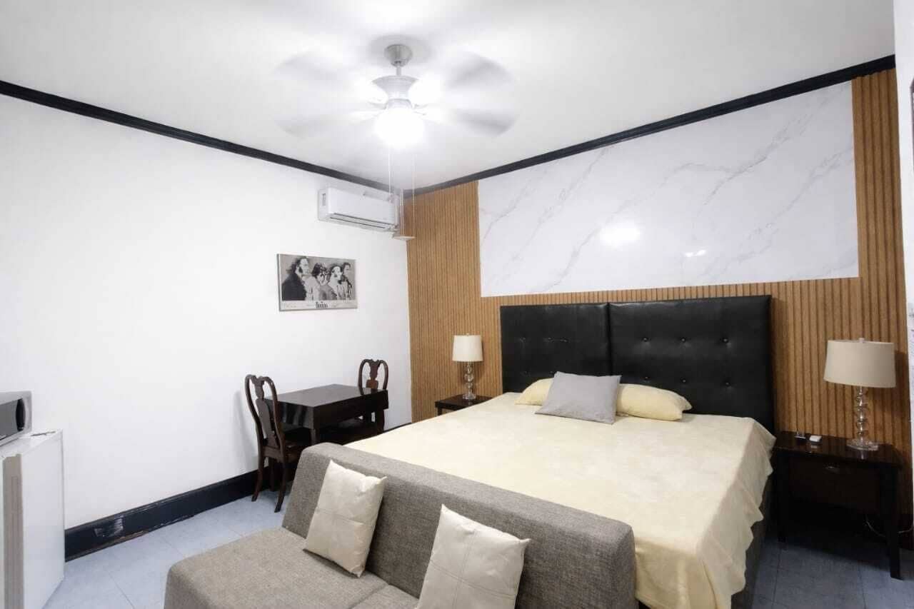 A hotel room with a bed, a sofa, a desk, and a chair.