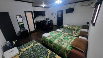 A hotel room with two single beds, a desk with a chair, a wardrobe, a mirror, and a television on the wall.