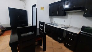 A compact kitchen with black cabinets, a countertop, a sink, and a stove. - Hotel Garcias Suites (Linares)