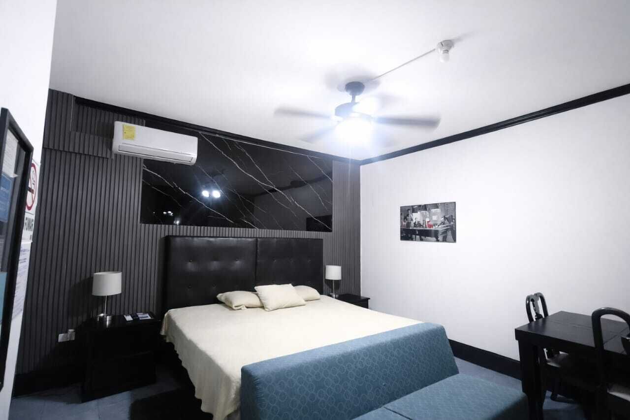 Ein Hotelzimmer mit Bett, Nachttisch, Lampe und Deckenventilator.
