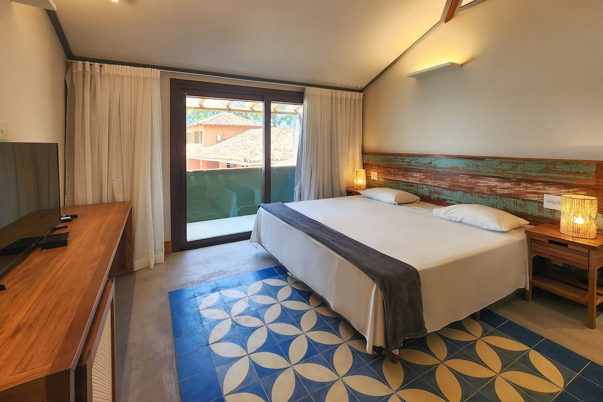Ein Hotelzimmer mit Bett, Schreibtisch, Lampe und Blick durch eine Schiebetür.