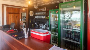 Una zona de bar con un refrigerador Heineken, una computadora portátil y un enfriador rojo.
