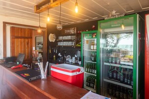 Uma área de bar com um refrigerador Heineken, um laptop e um cooler vermelho.
