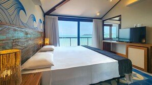 Una habitación de hotel con una cama grande, televisión y vista al mar.