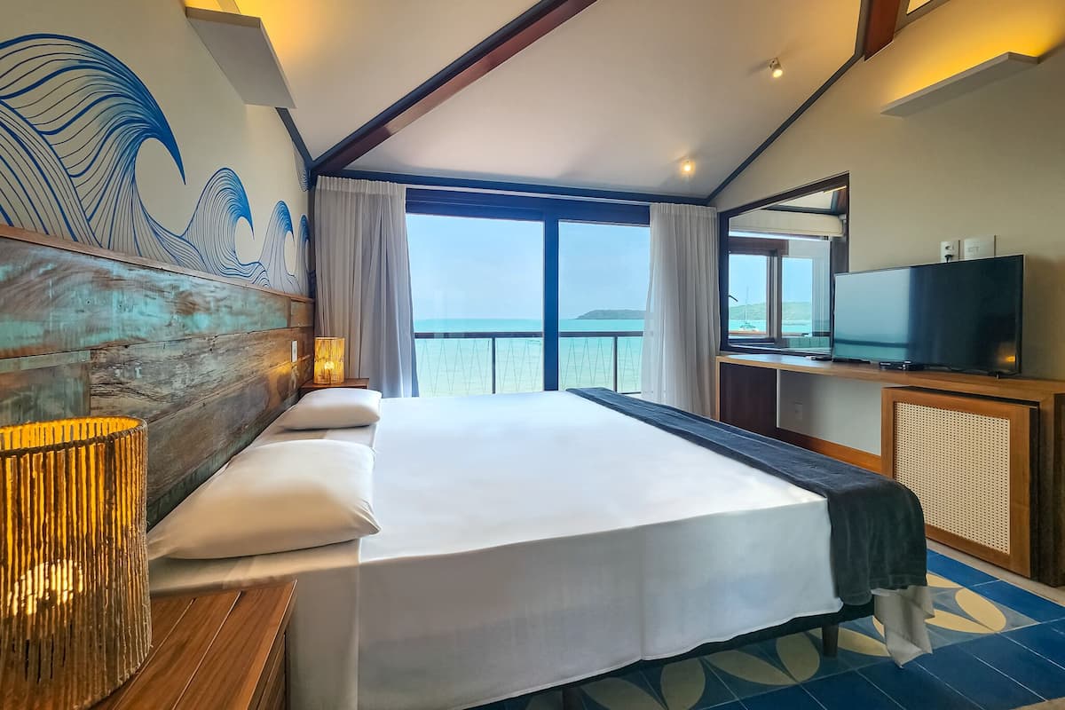 Ein Hotelzimmer mit einem großen Bett, einem Fernseher und Meerblick.