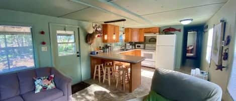 A compact living space with a kitchenette, a dining area, and a seating area with a sofa and a chair.