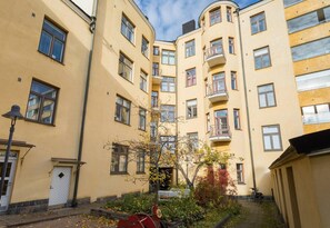A multi-story residential building with balconies, a small garden area, and a bicycle parked outside. - Cosy Quiet Apartment Close to the Sea and Parks (Helsinki)