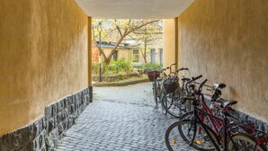 A narrow corridor with a tiled floor, flanked by yellow walls and a stone base. Several bicycles are parked along the right side. - Cosy Quiet Apartment Close to the Sea and Parks (Helsinki)