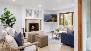 Una sala de estar con chimenea, asientos y un ventanal grande.