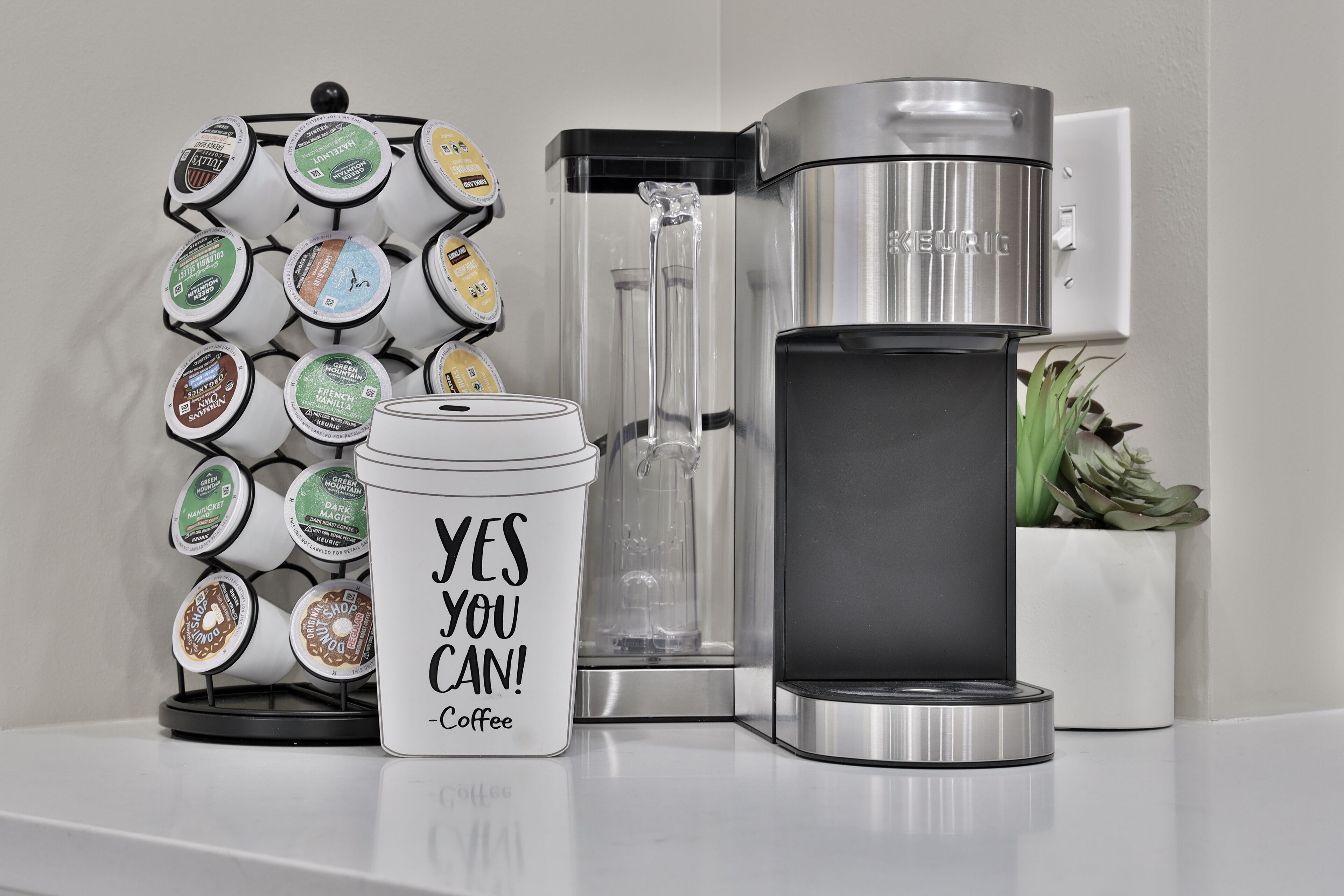 A coffee maker, a coffee pod holder, and a water dispenser on a countertop.