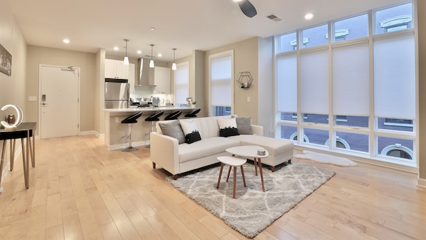 Un salon moderne avec un canapé blanc, une table basse et un ventilateur de plafond.