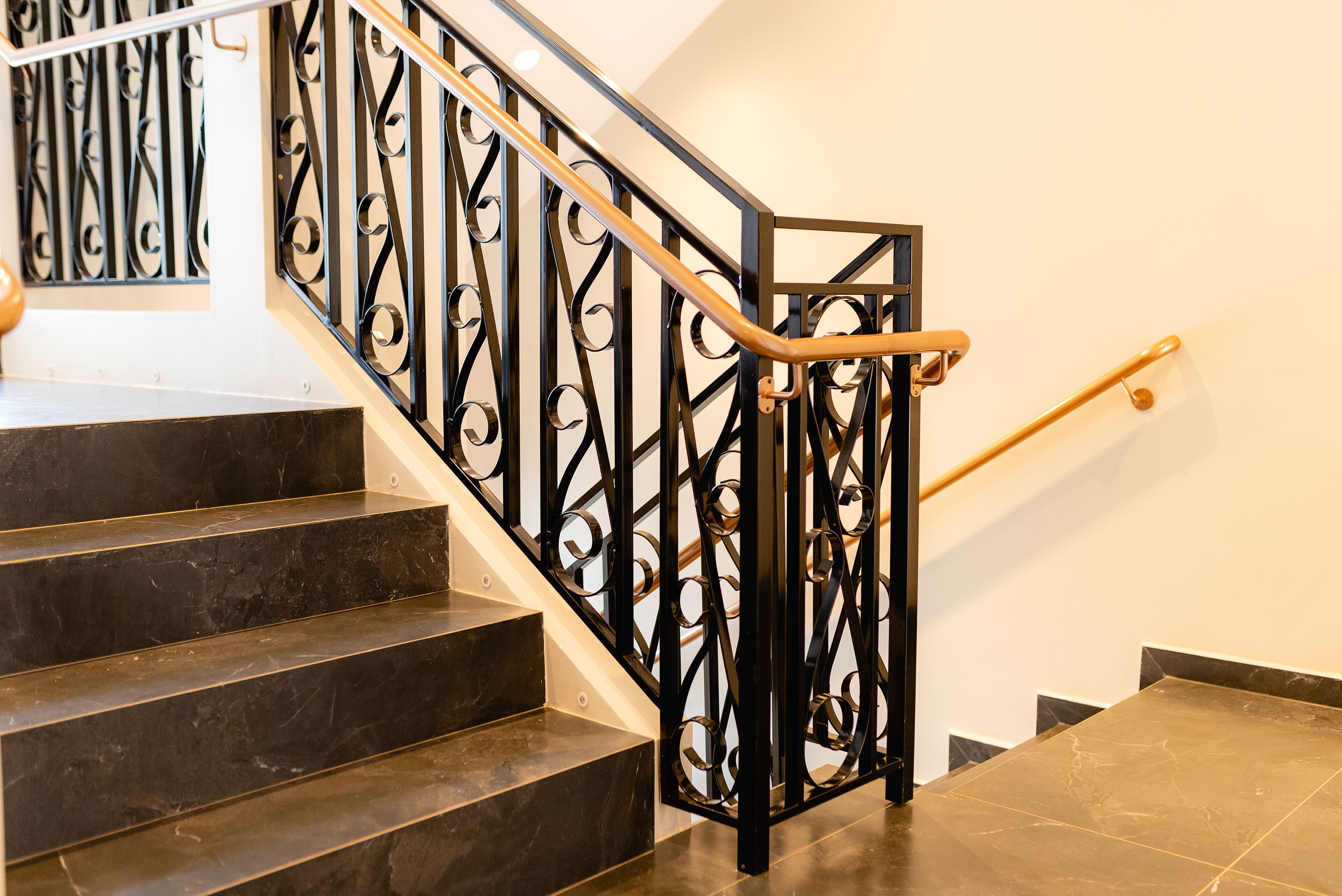 A staircase with black metal railings and wooden handrails.