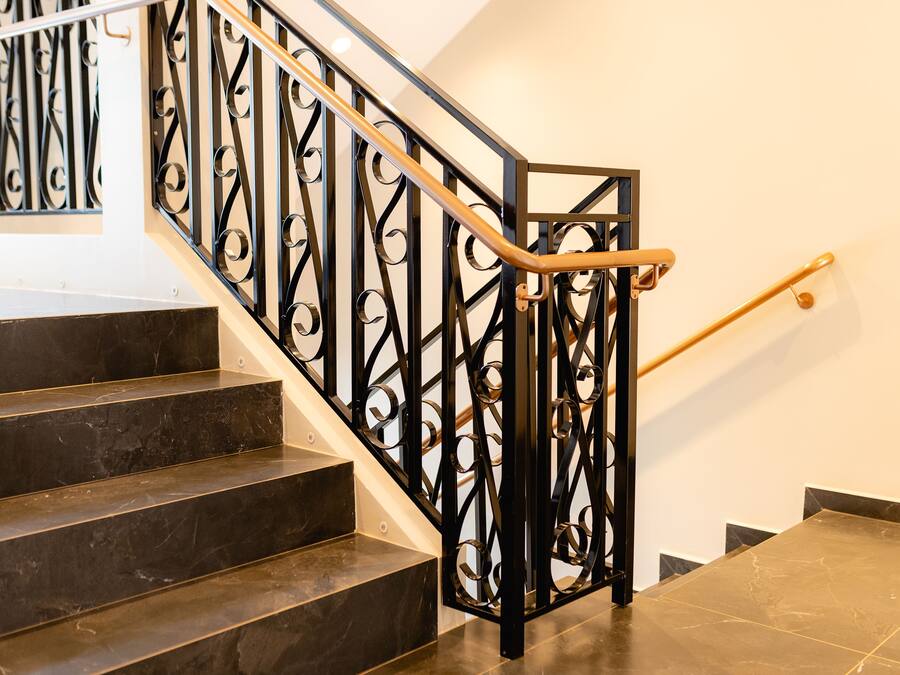 Una escalera con barandales de metal negro y pasamanos de madera.
