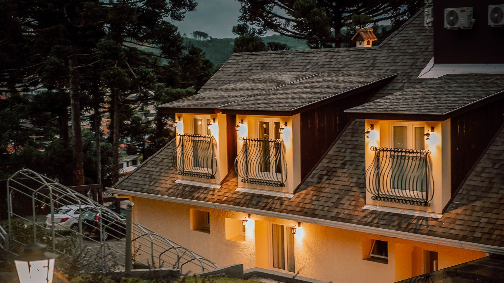 Una casa a due piani con tetto spiovente, diversi balconi con ringhiere in metallo e una scala che conduce al piano superiore.