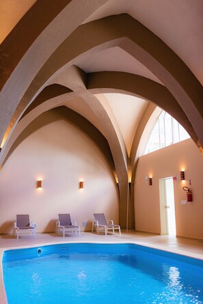 Una piscina techada, sillones reclinables de piscina