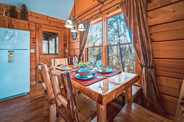 A wooden cabin interior with a dining table set for four, surrounded by wooden chairs.